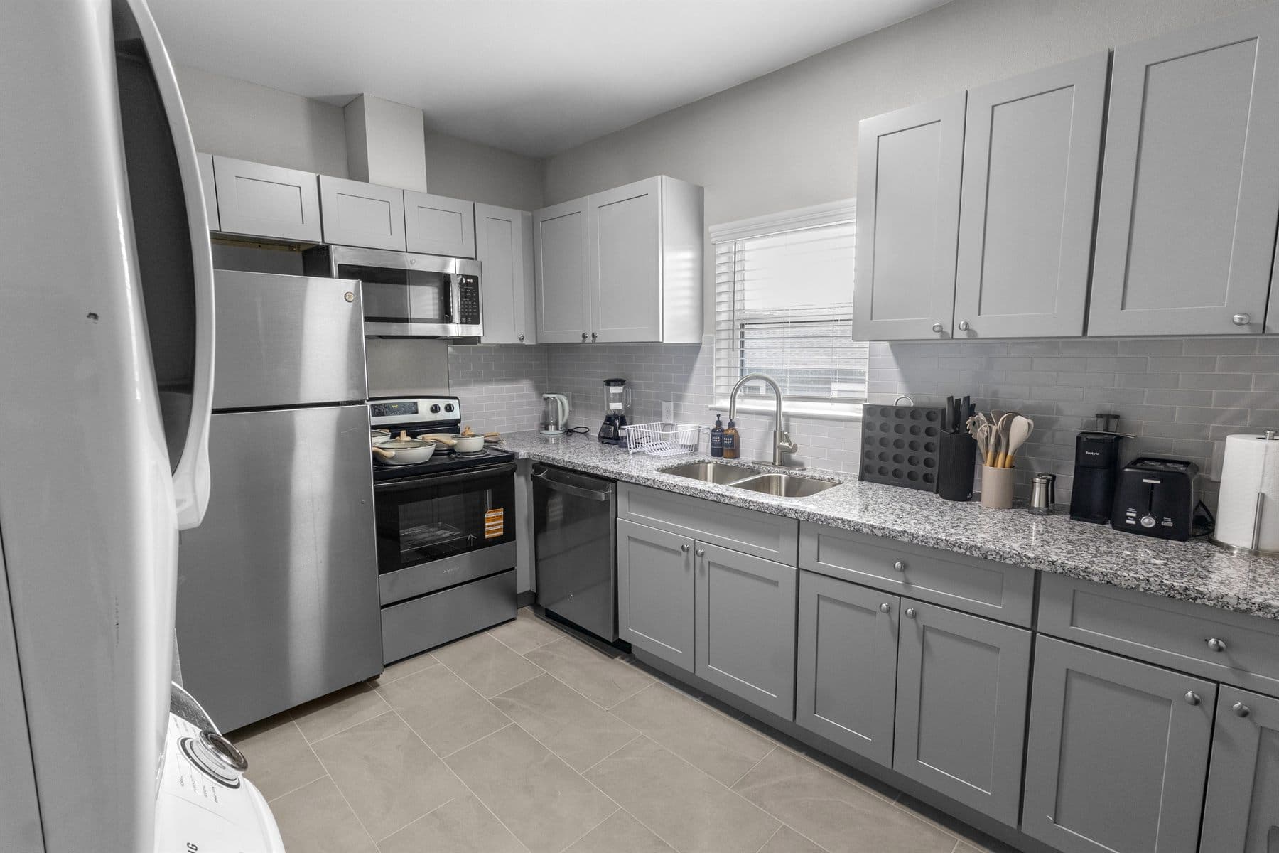 Bright kitchen with gray cabinets and stainless appliances, finished by the Reborn group