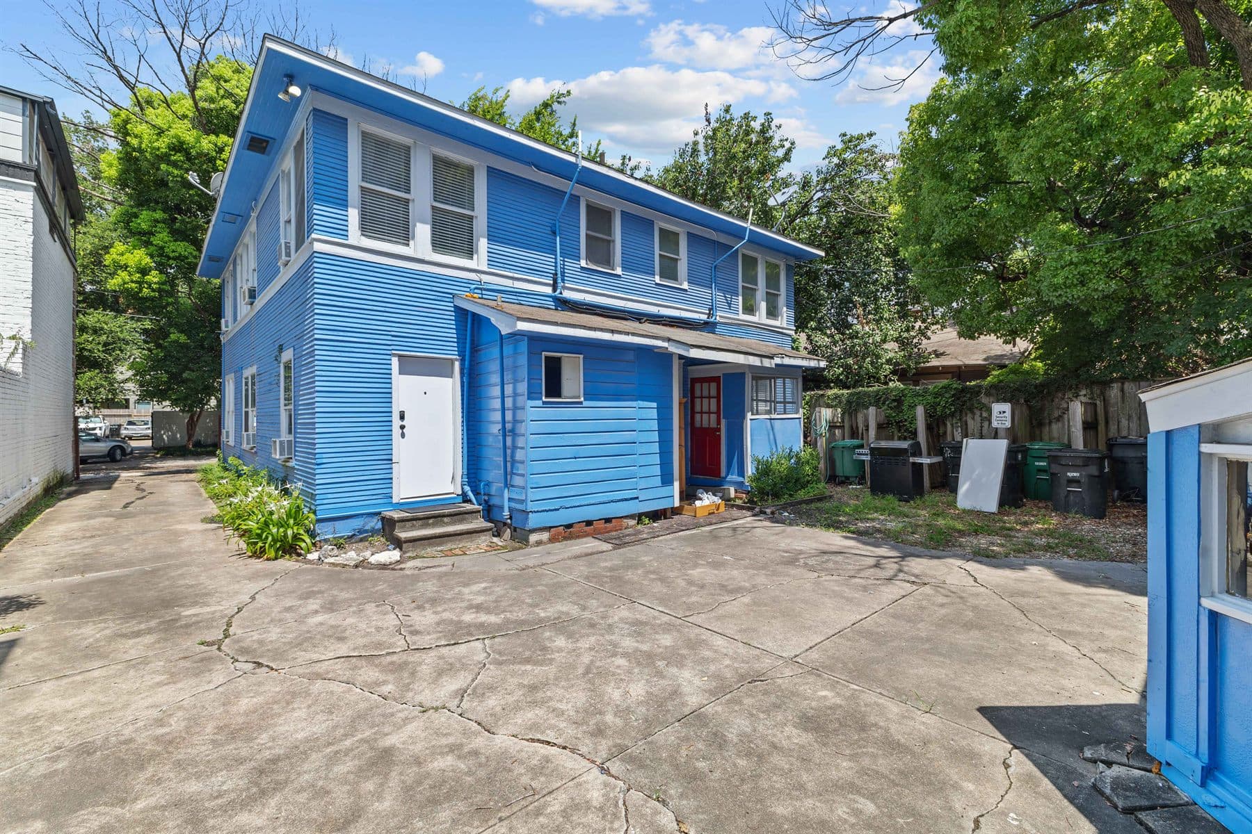 Two-story blue craftsman exterior with white door and mature trees, finished by the Reborn group