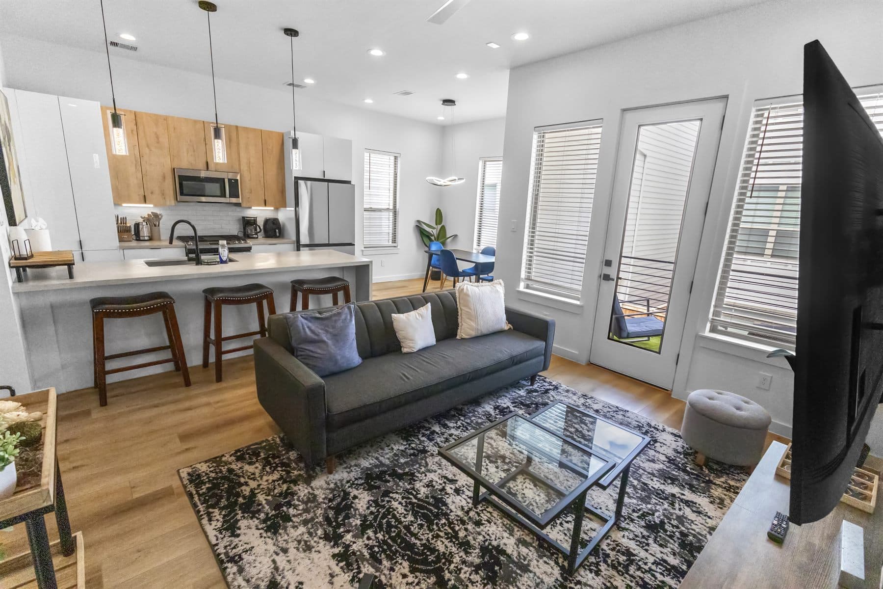 Open-concept kitchen island and living area with door to a private balcony, finished by the Reborn group