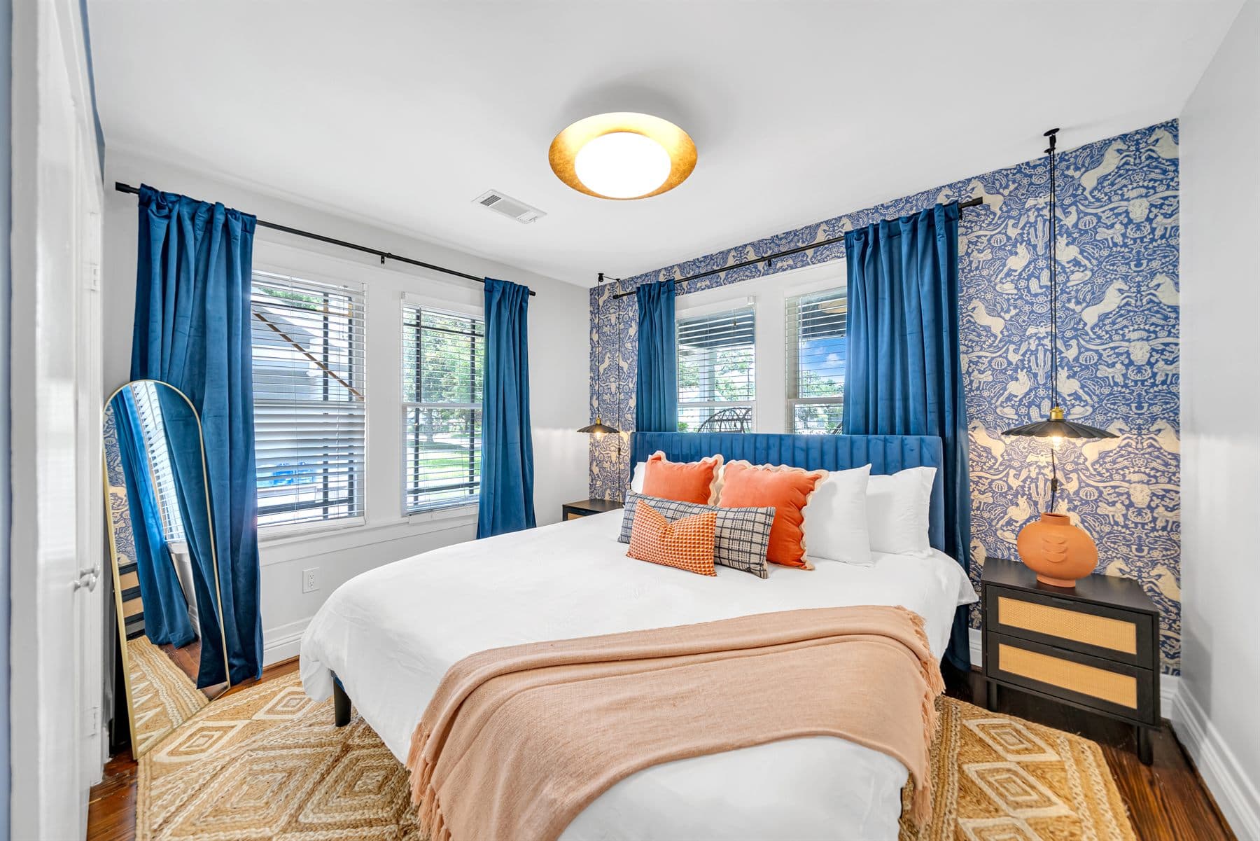 Bedroom with blue floral curtains and orange accent pillows, finished by the Reborn group