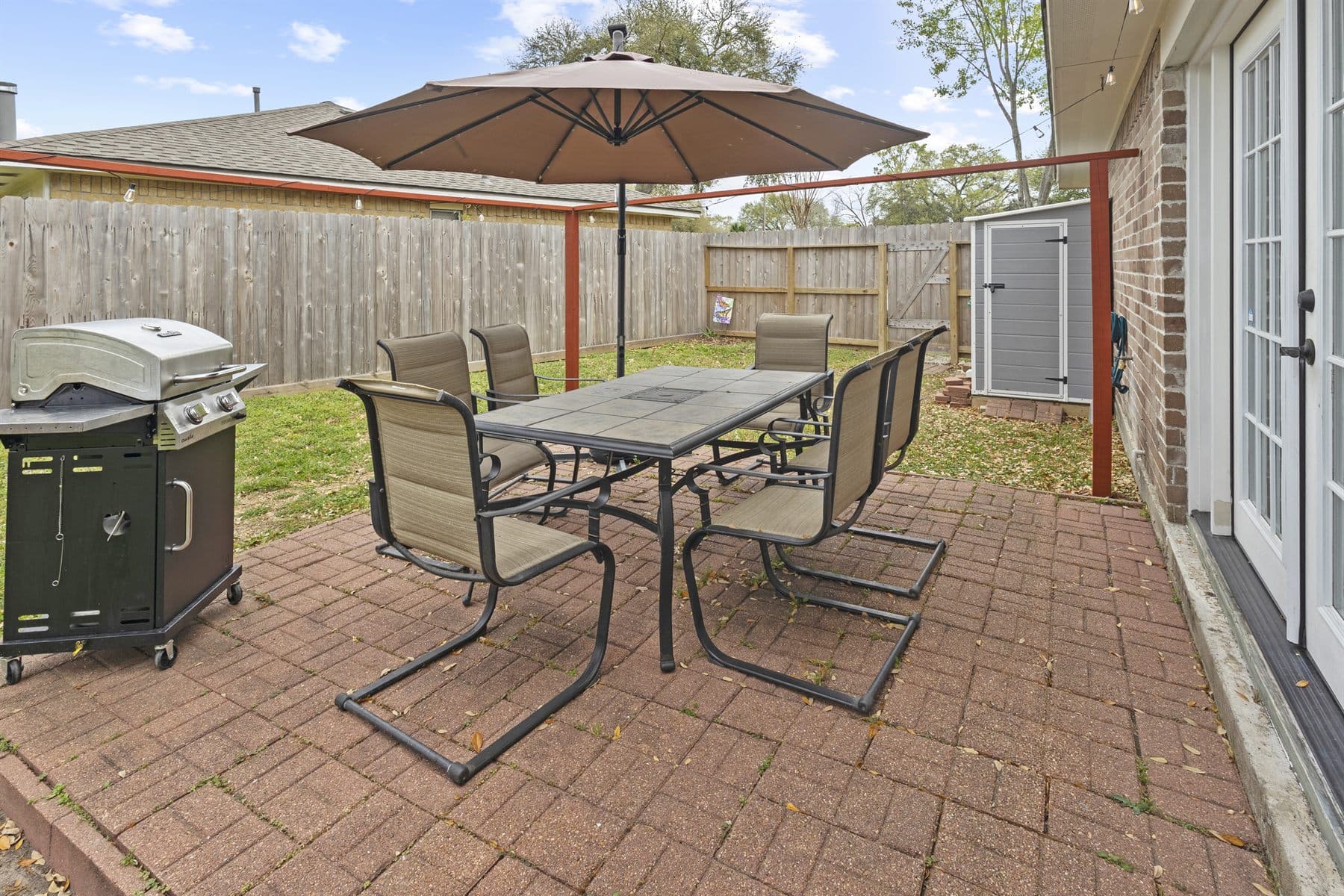 Covered brick patio with dining set and grill, finished by the Reborn group