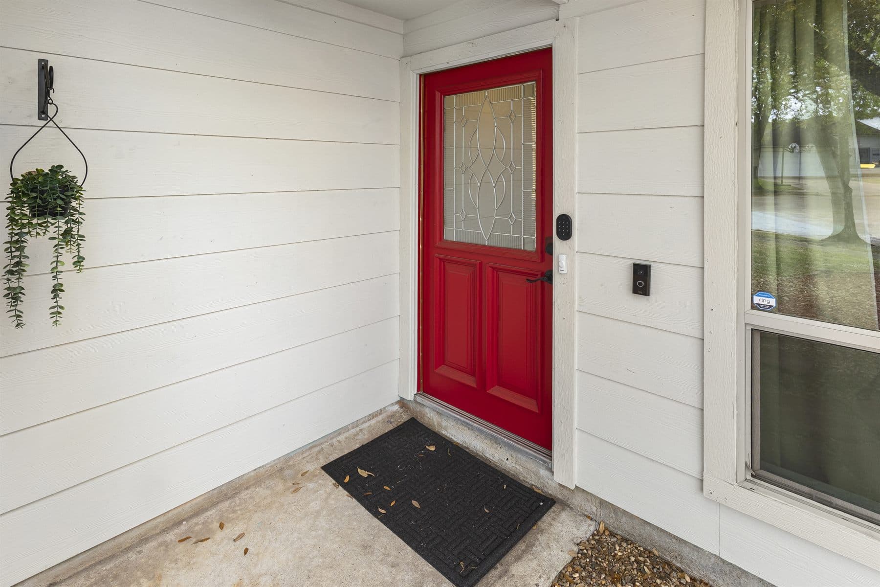 Red front door with white siding and hanging plant, finished by the Reborn group