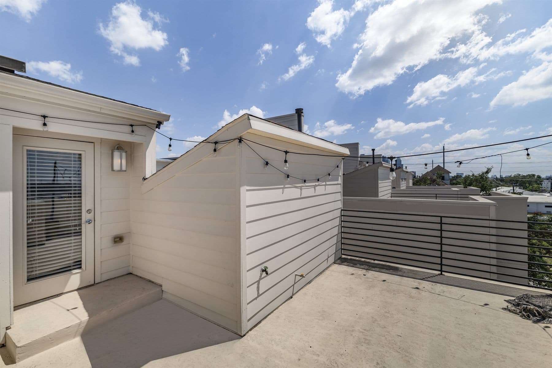 Rooftop terrace with string lights and a distant skyline view, finished by the Reborn group