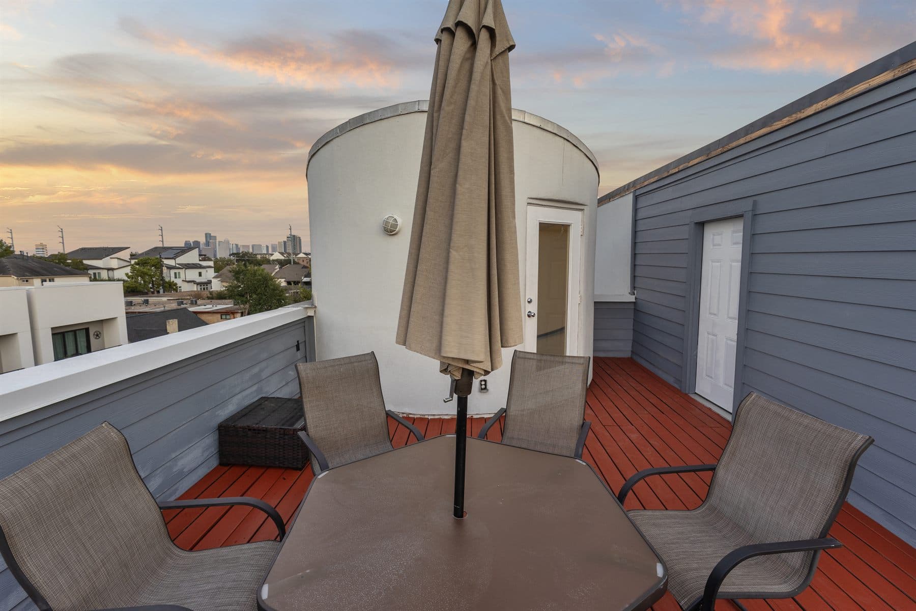 Corner of a rooftop deck with patio umbrella and seating, finished by the Reborn group