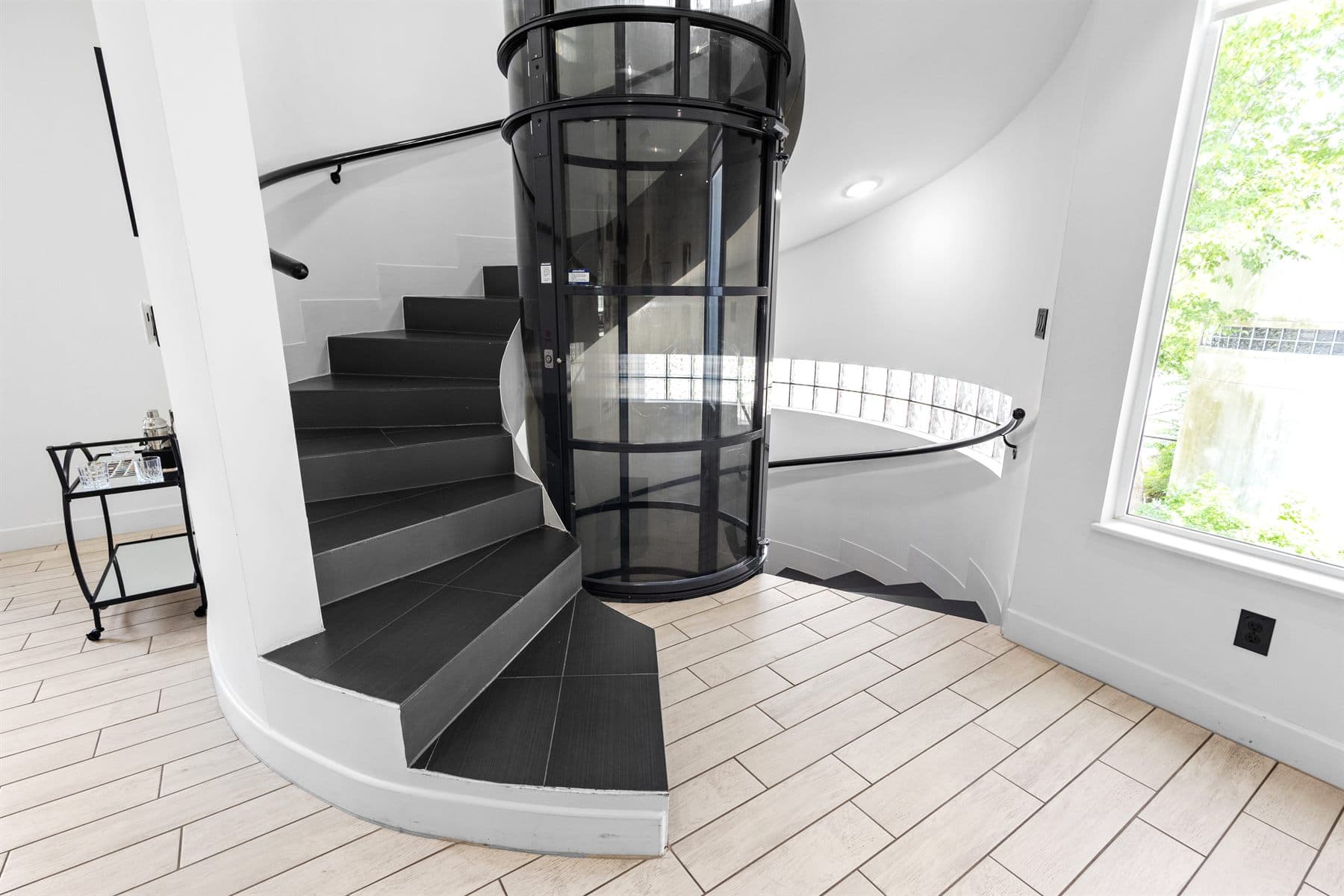 Spiral staircase wrapping a glass residential elevator, finished by the Reborn group
