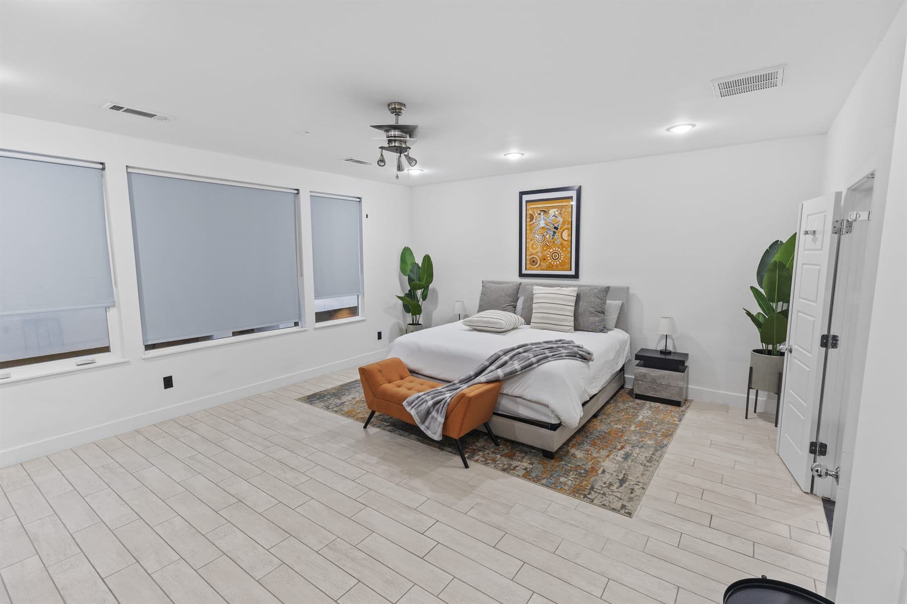 Bright primary bedroom with styled bed and plants, finished by the Reborn group