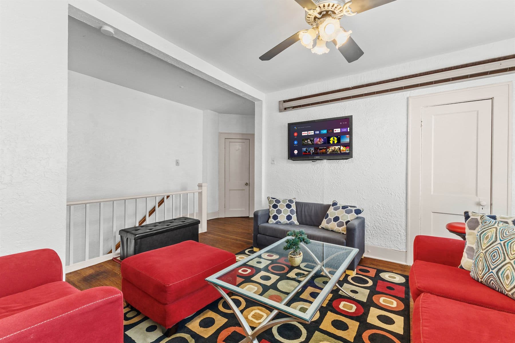 Living room with red sofa, blue accent chair and dark wood floors, finished by the Reborn group
