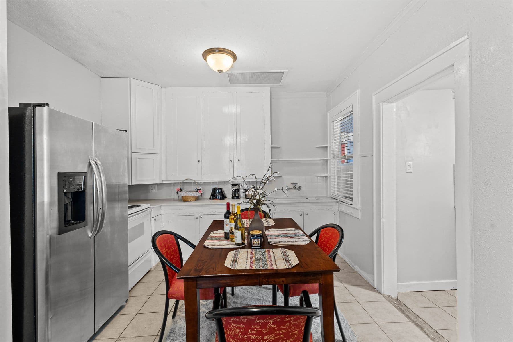 Kitchen with stainless fridge, wood dining table and tile floor, finished by the Reborn group