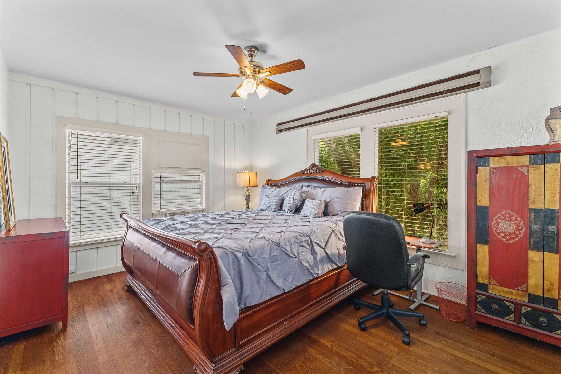 Bedroom with dark wood sleigh bed and bright window, finished by the Reborn group