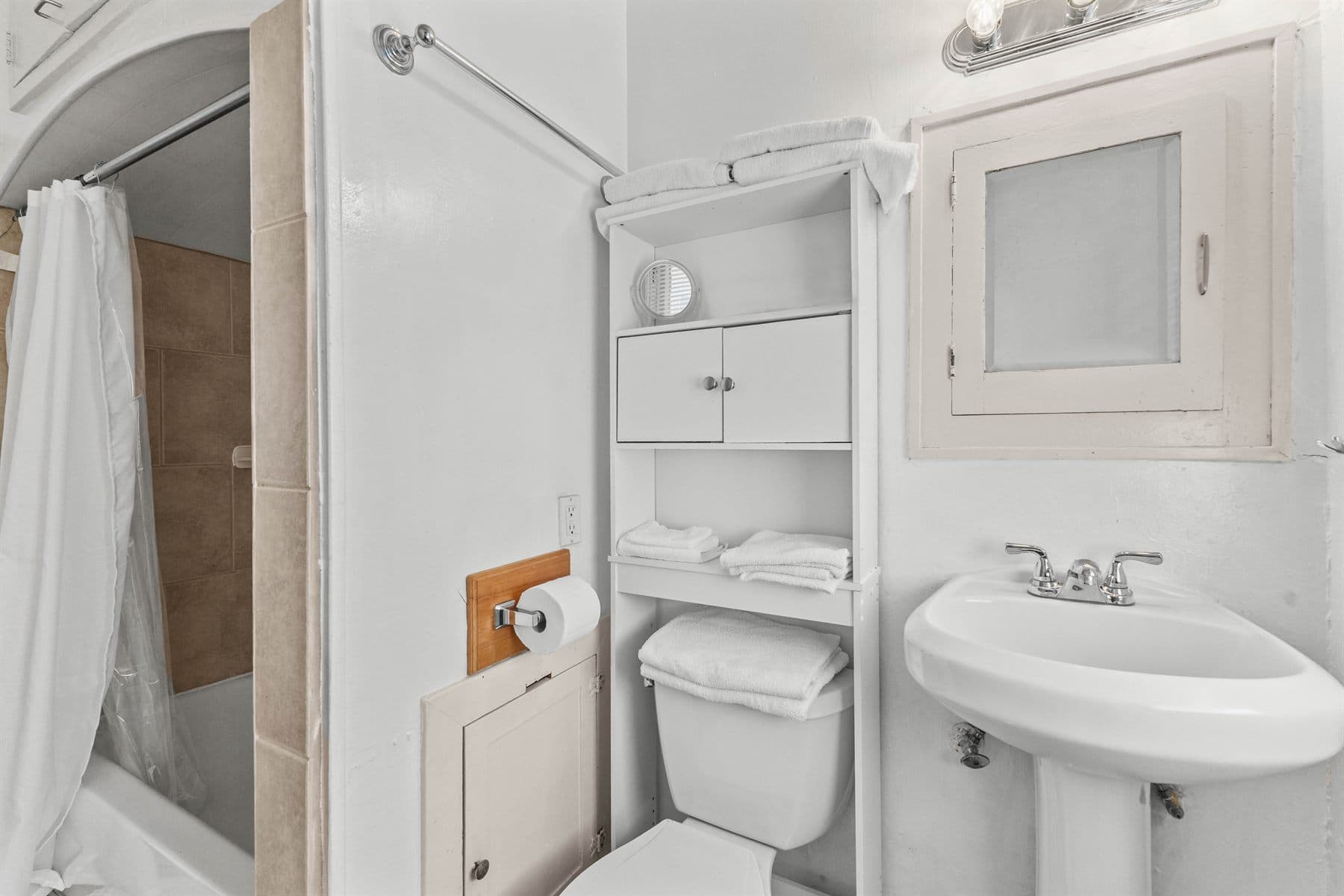 Bath with white pedestal sink and corner cabinet, finished by the Reborn group