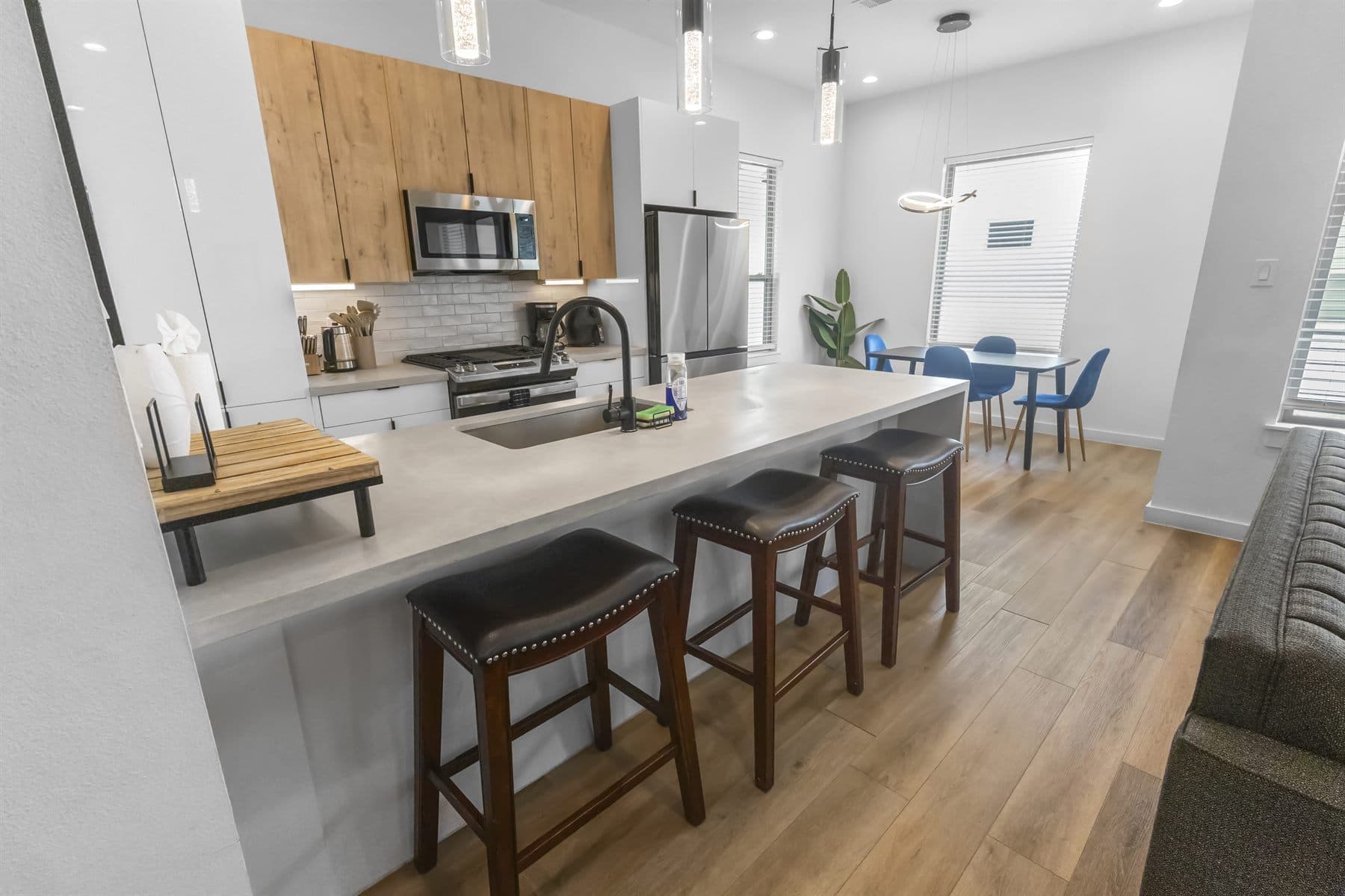 Kitchen island with pendant lights, white cabinetry and wood barstools, finished by the Reborn group