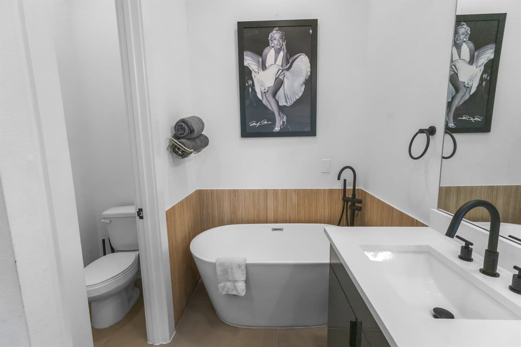 Freestanding soaking tub with dual vanity and matte black fixtures, finished by the Reborn group