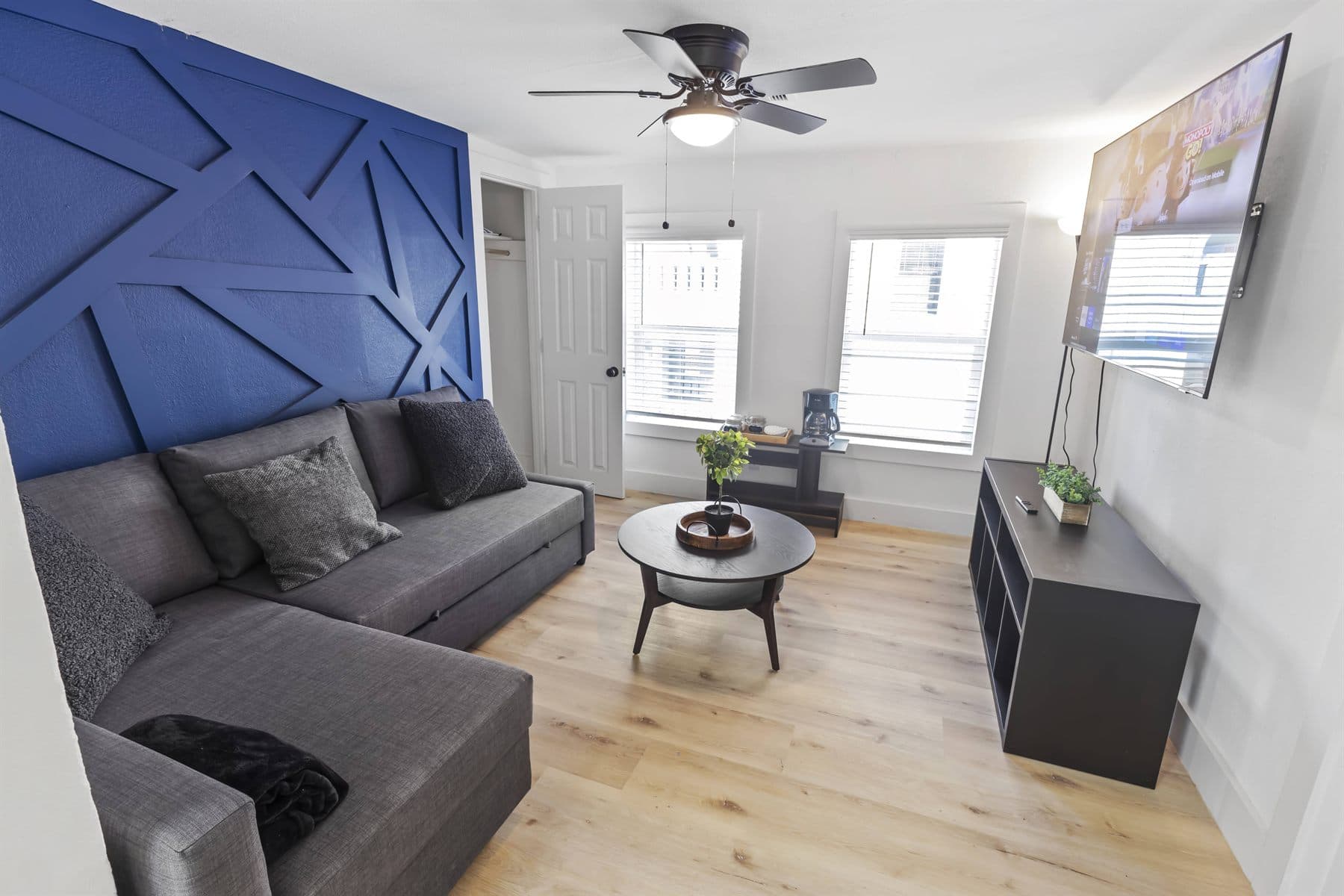 Living room with blue barn-door accent wall and gray sofa, finished by the Reborn group