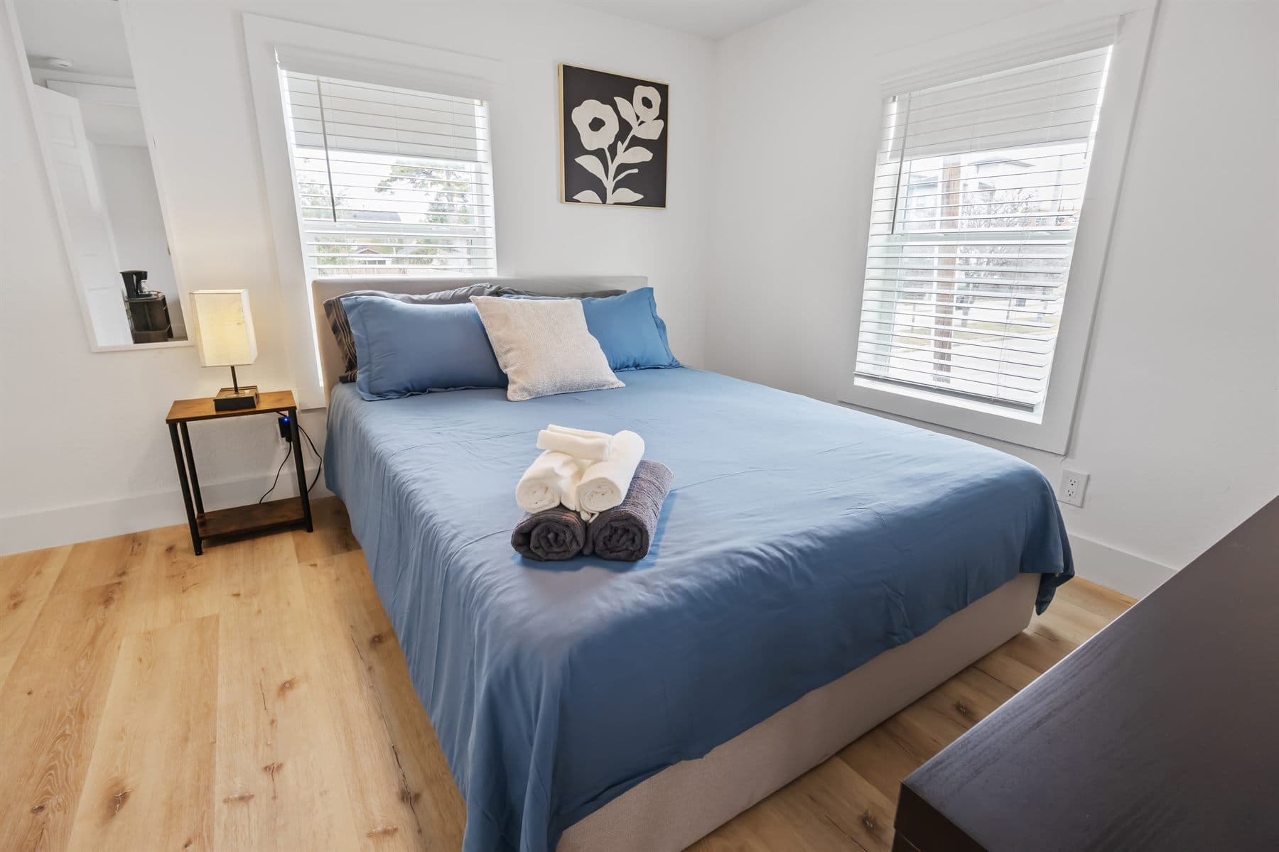 Bedroom with blue bedding and wall-mounted TV, finished by the Reborn group