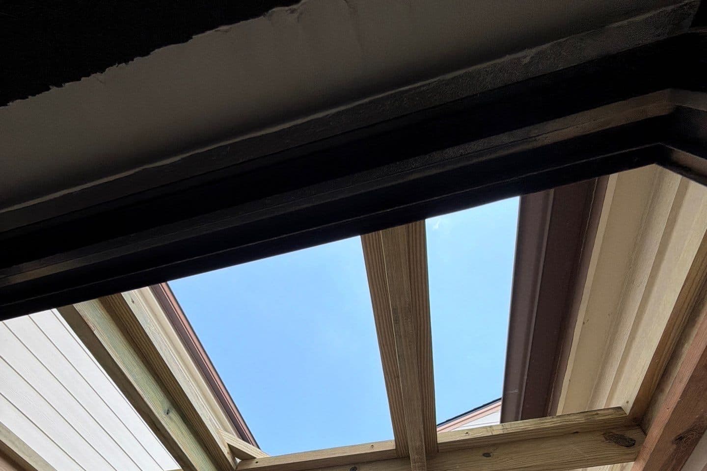 New pergola rafters framed against the sky over the back patio