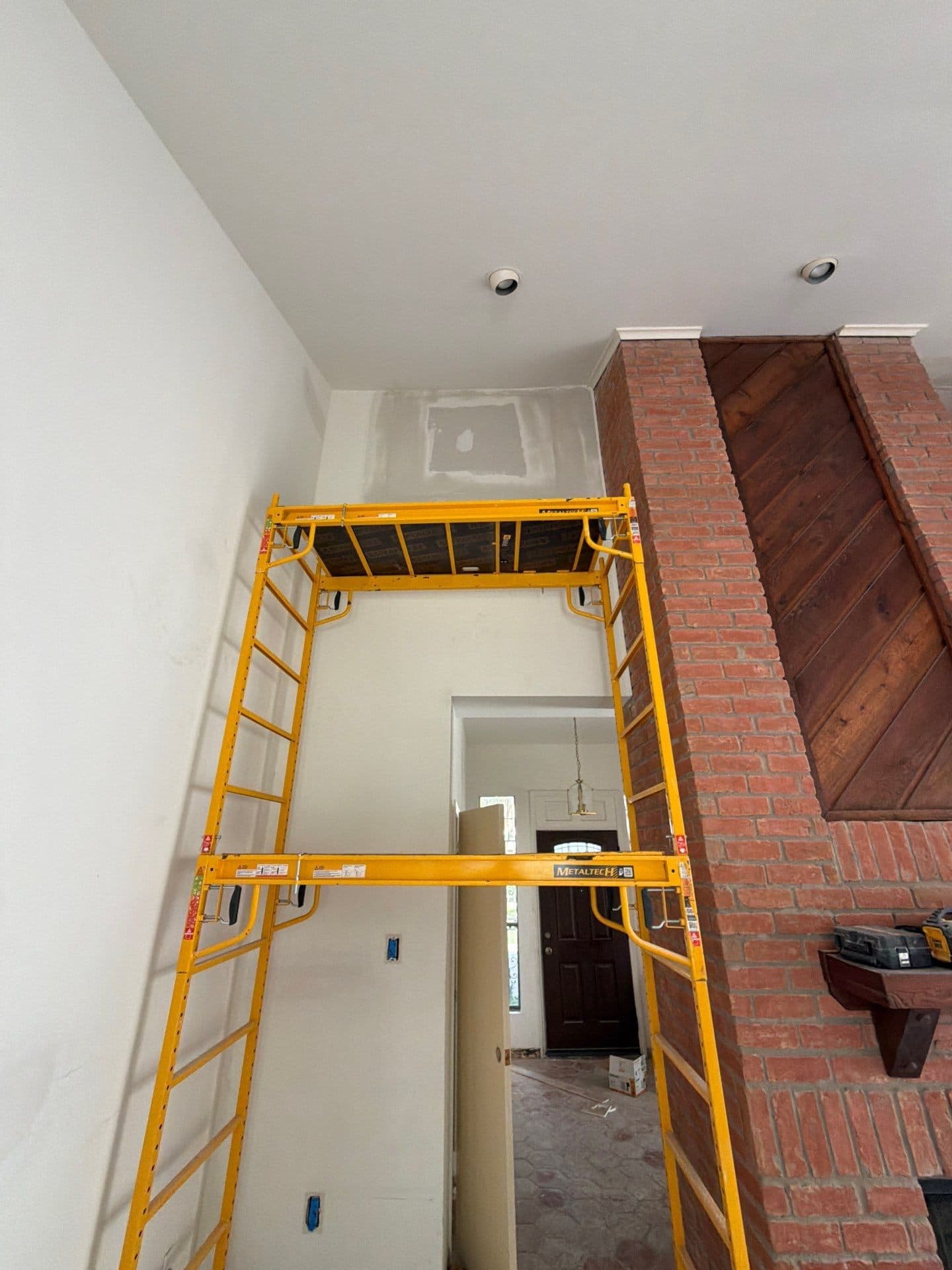 Scaffolding at the two-story brick fireplace and wood paneling