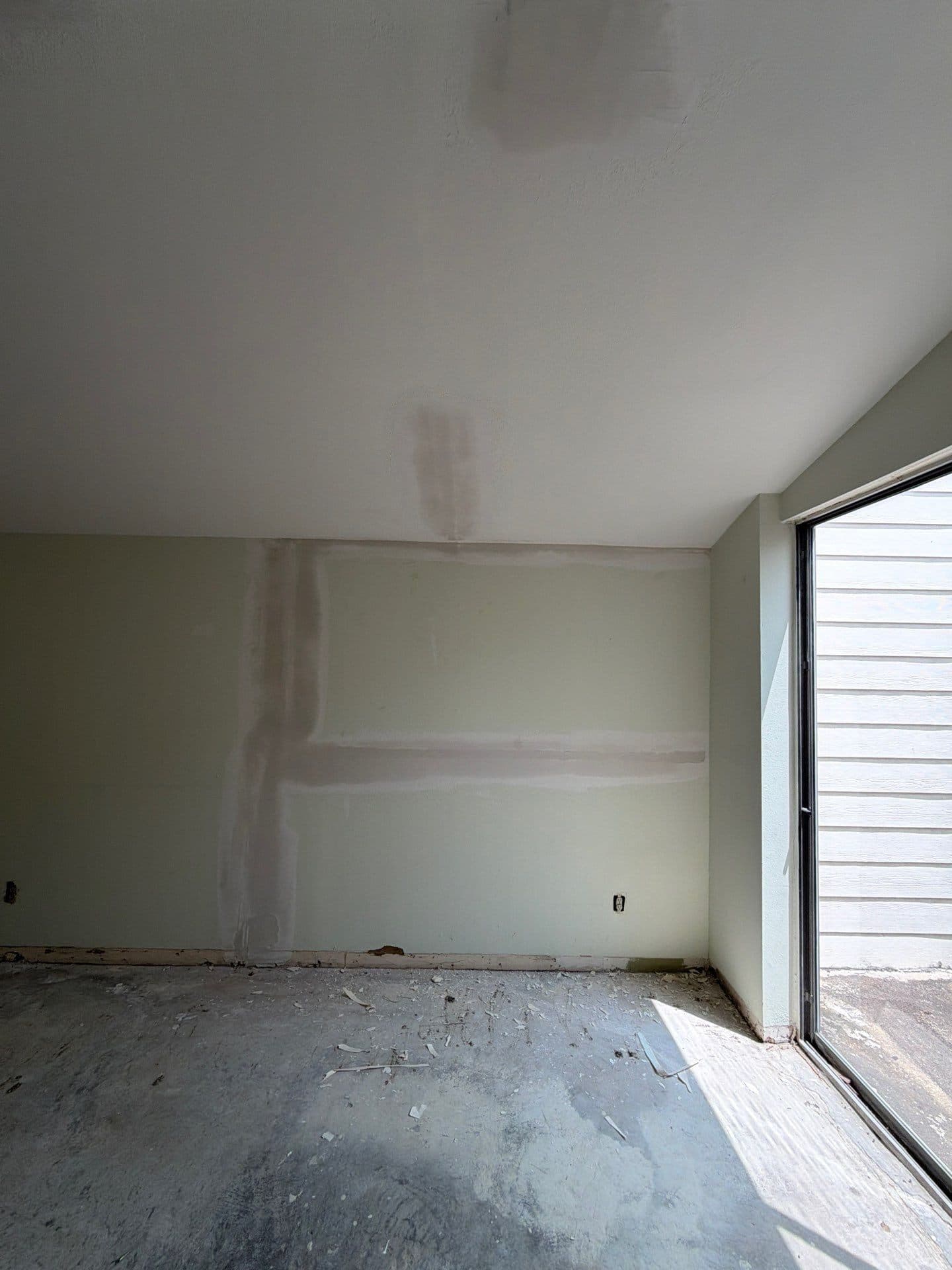 Bedroom taped and floated, light through the slider