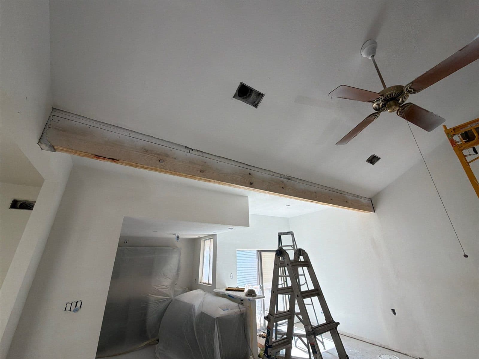 Painted vaulted room with exposed wood beam and new ceiling fan