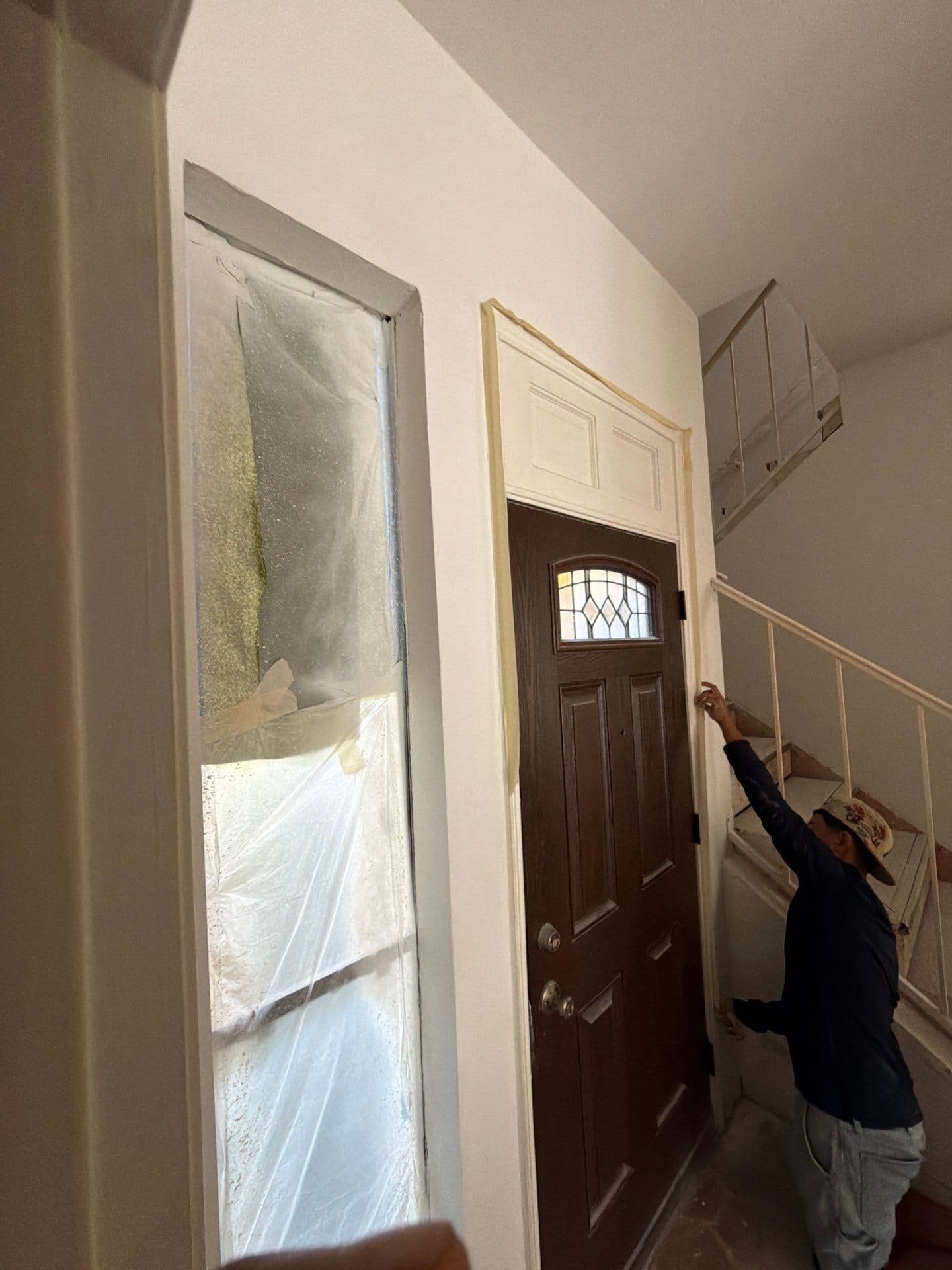 Painter working the front door trim in the painted entry