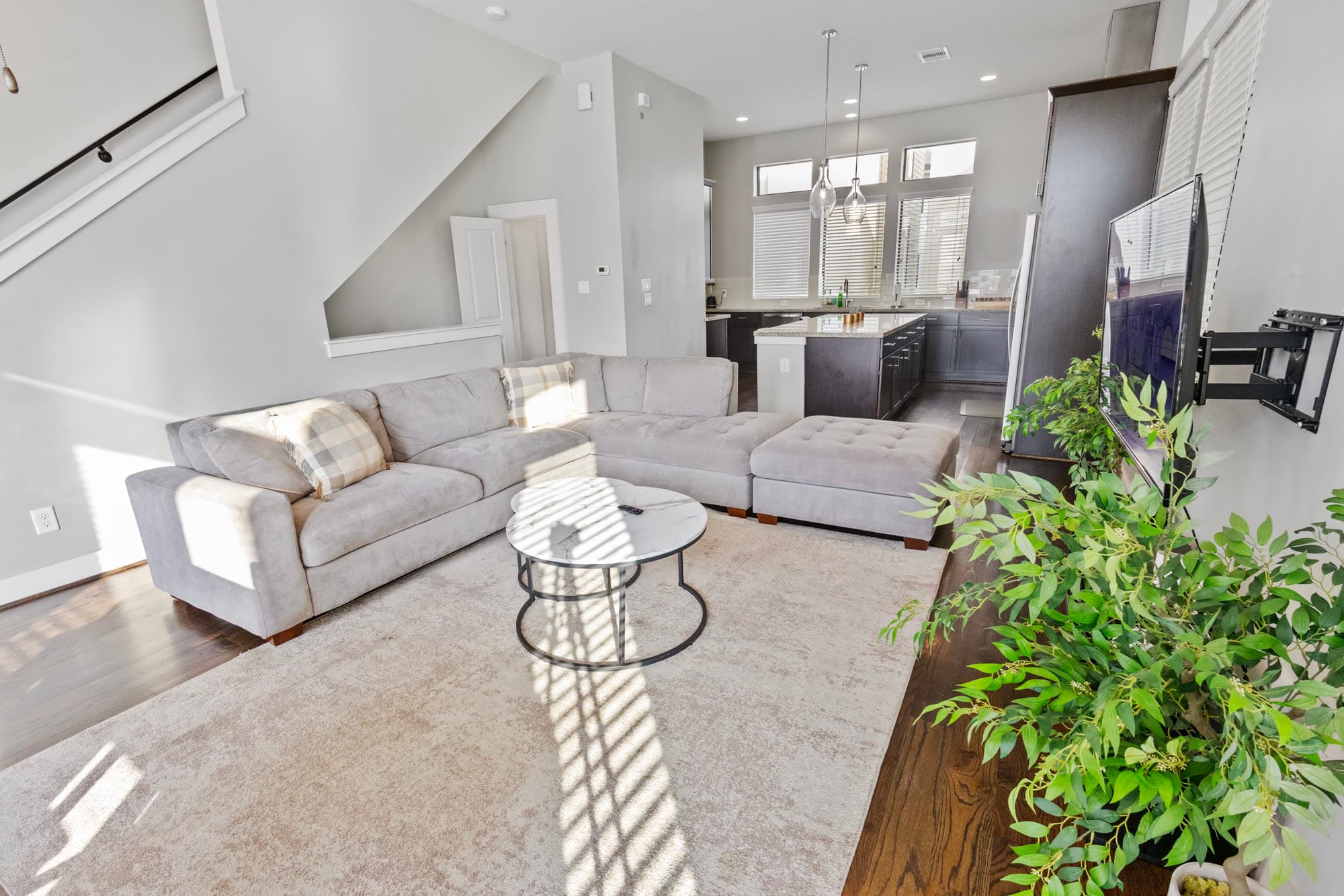Open living room with staircase and kitchen island, finished by the Reborn group