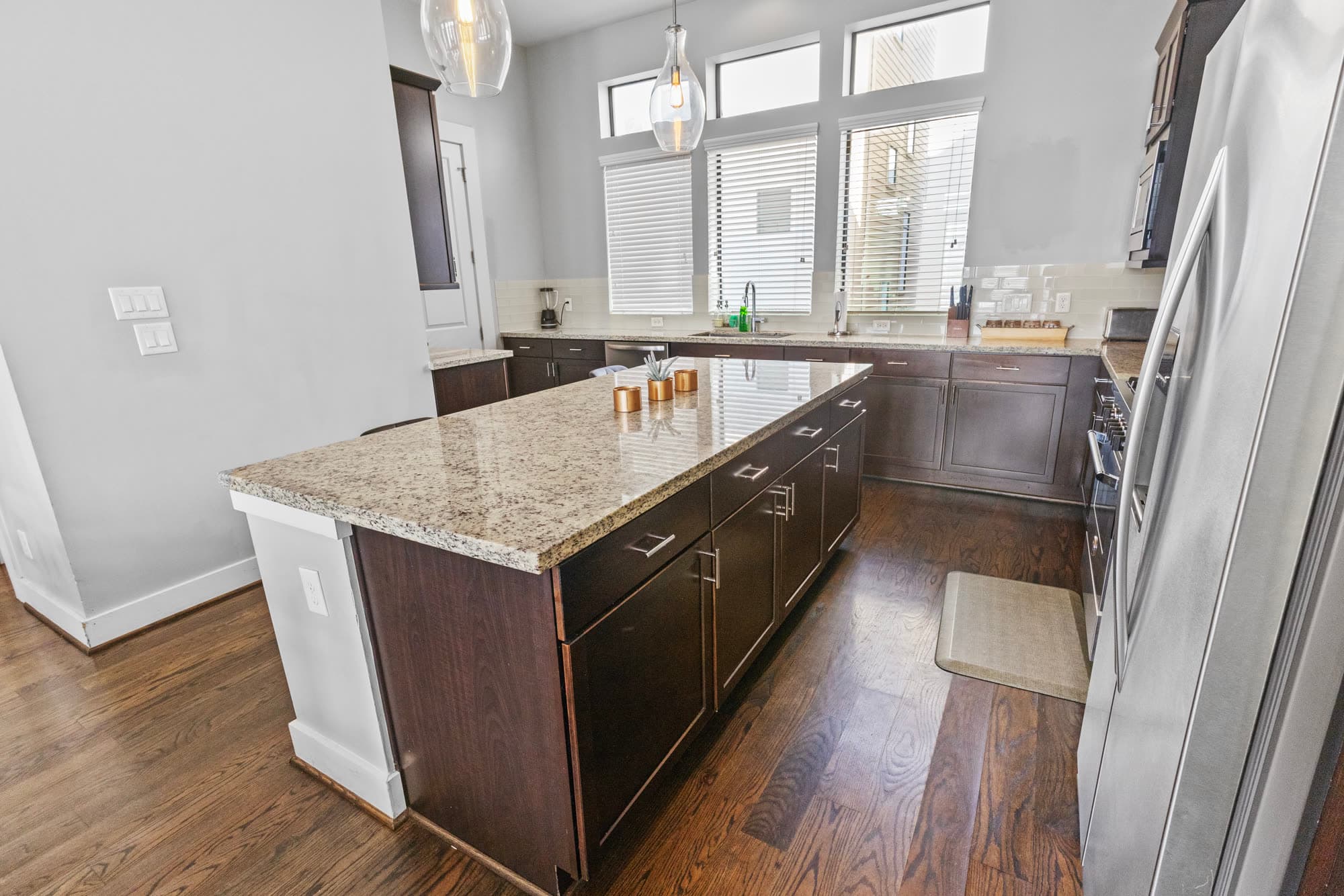 Kitchen with granite island, espresso cabinets, and pendant lights, finished by the Reborn group