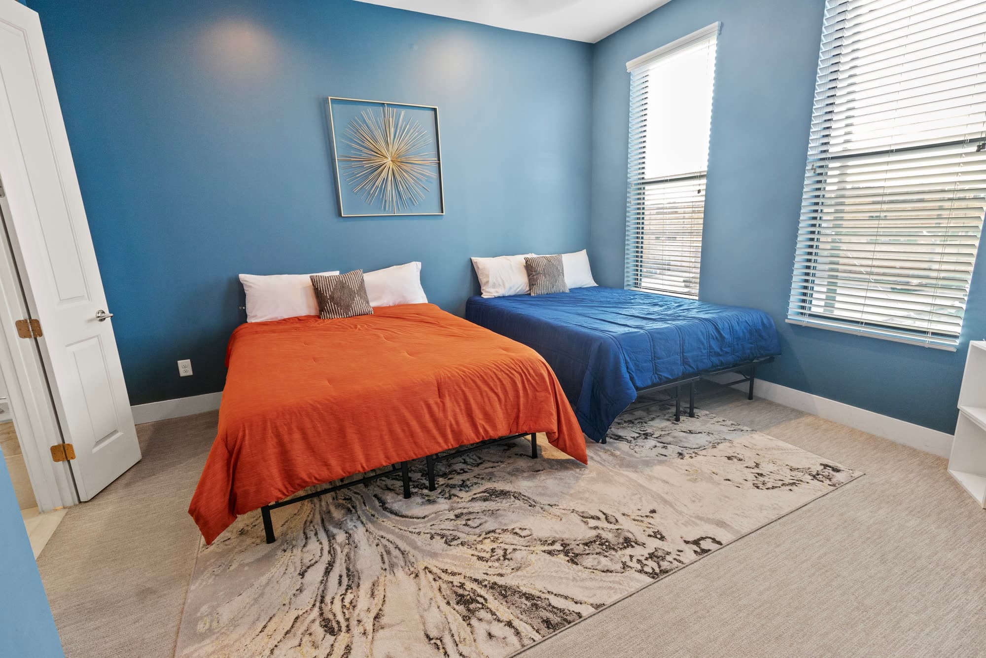 Bedroom with a blue accent wall and styled twin beds, furnished by the Reborn group