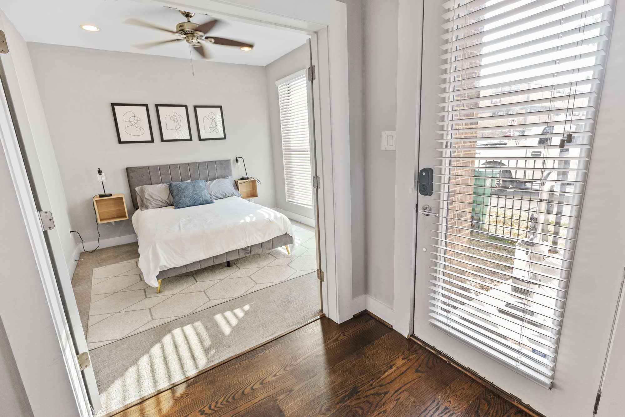 Bedroom with upholstered headboard seen through an open doorway, furnished by the Reborn group