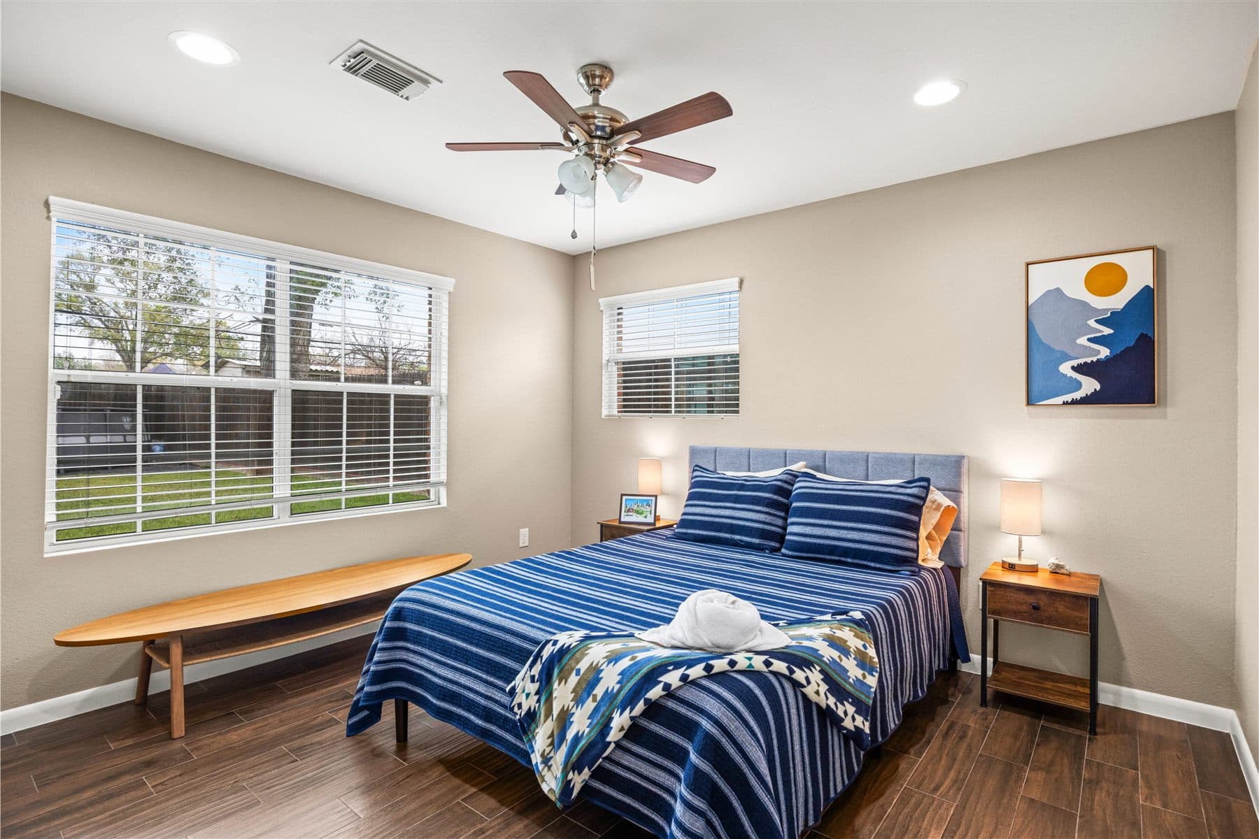 Bedroom with navy bedding and a styled reading bench, furnished by the Reborn group
