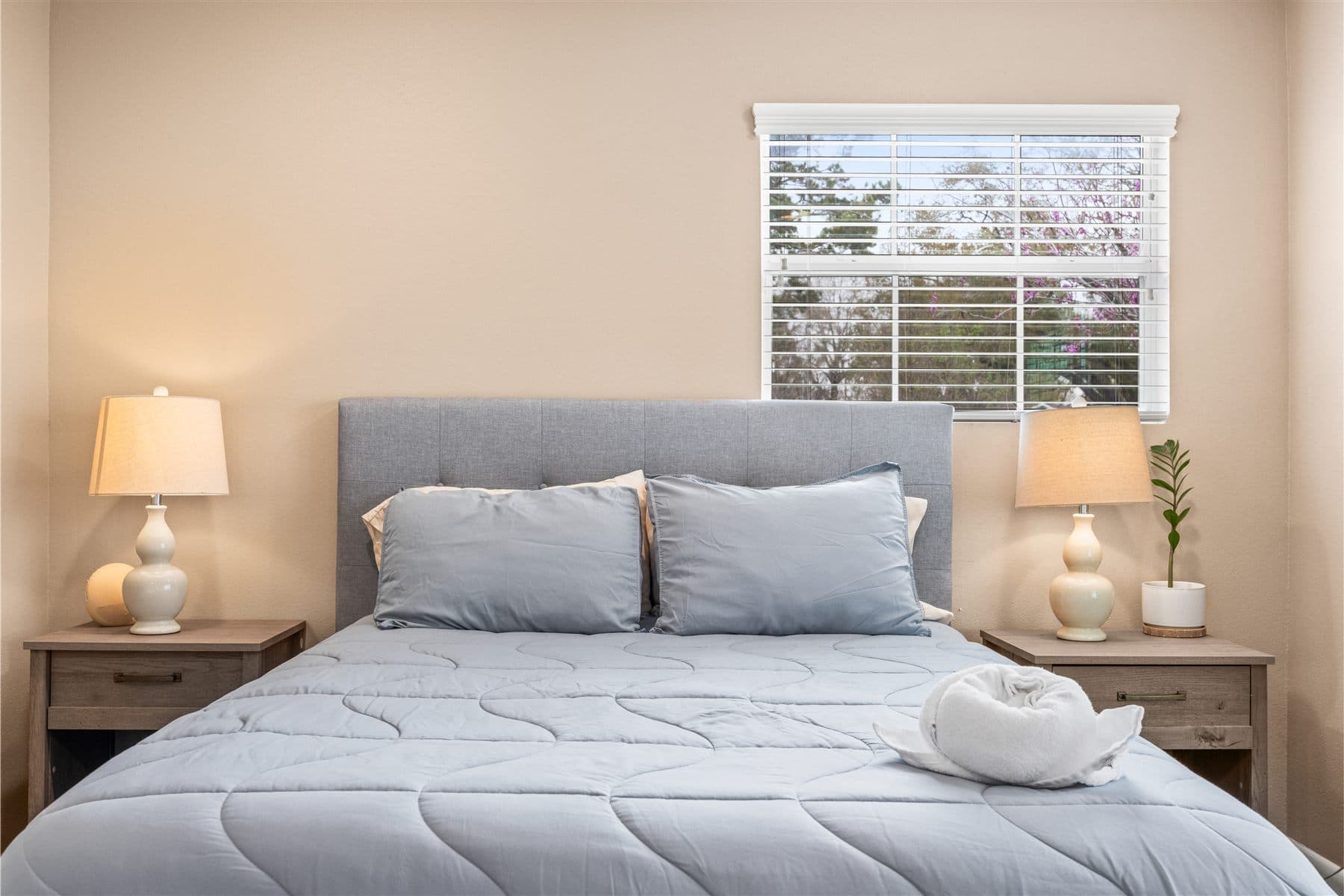 Bedroom with an upholstered headboard and paired lamps, furnished by the Reborn group