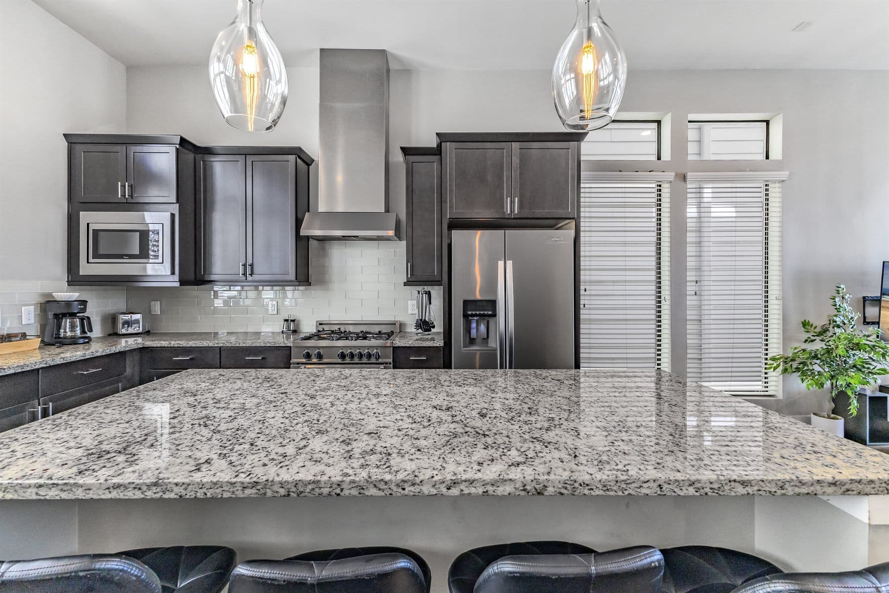 Dark cabinet kitchen island with granite counters and stainless hood, finished by the Reborn group