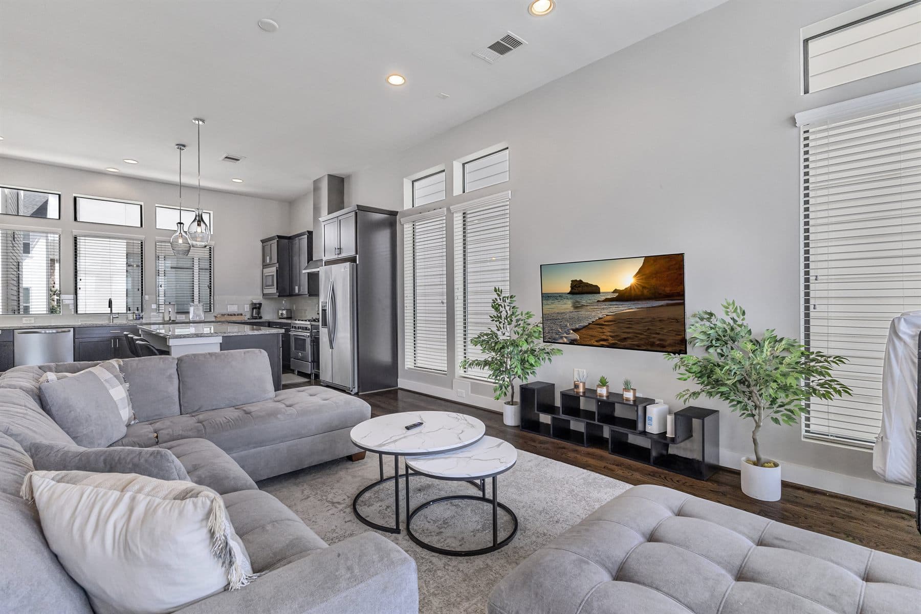 Vaulted great room with sectional, plants and stainless kitchen, finished by the Reborn group