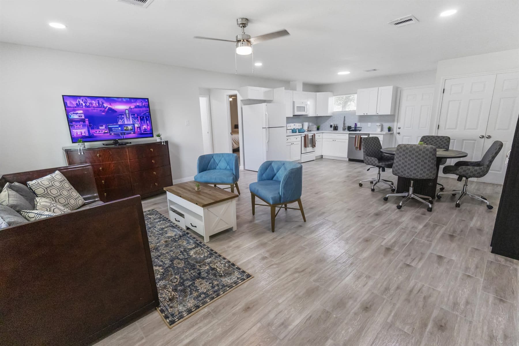 Living and dining area with dark accent chairs and oak floors, finished by the Reborn group