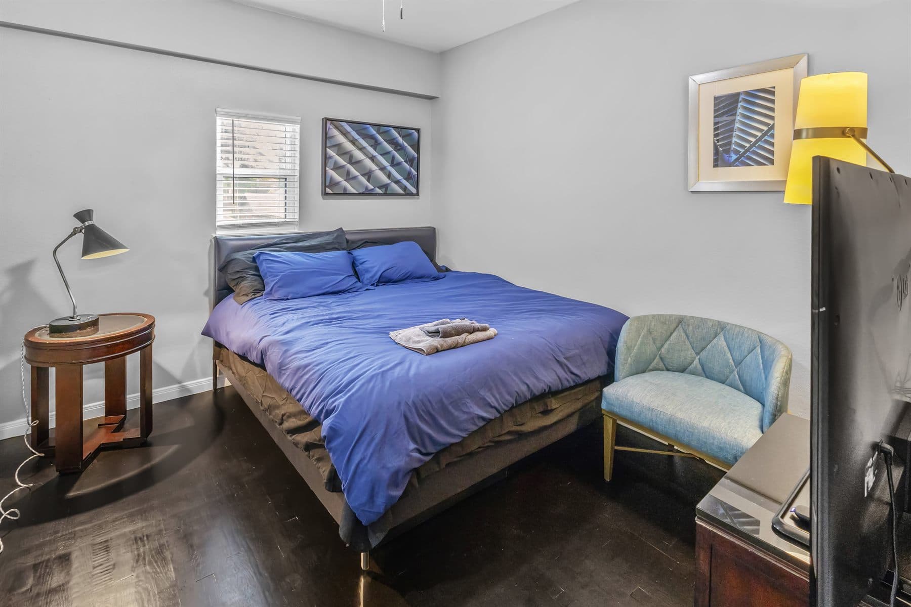 Bedroom with navy linens and teal accent chair, finished by the Reborn group