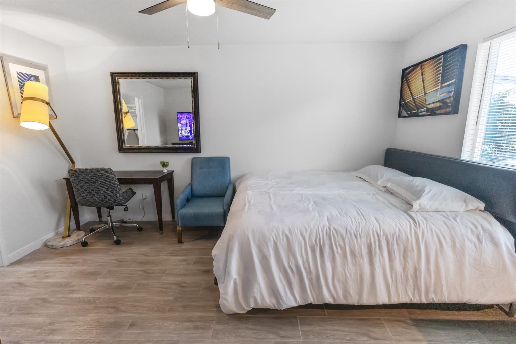 Bedroom with desk, teal chair and window light, finished by the Reborn group