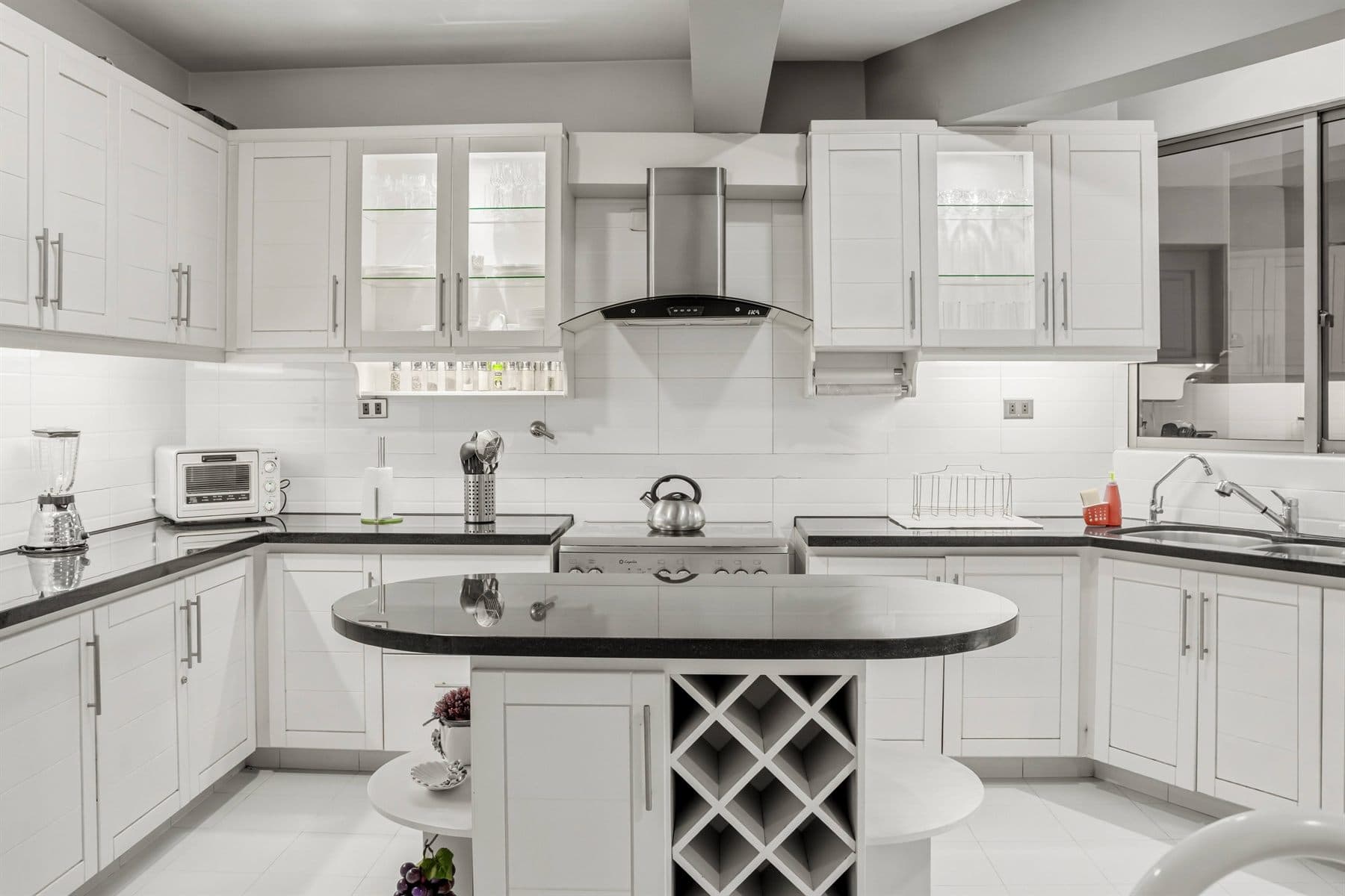 Modern white kitchen with black granite island and pendant lights, finished by the Reborn group