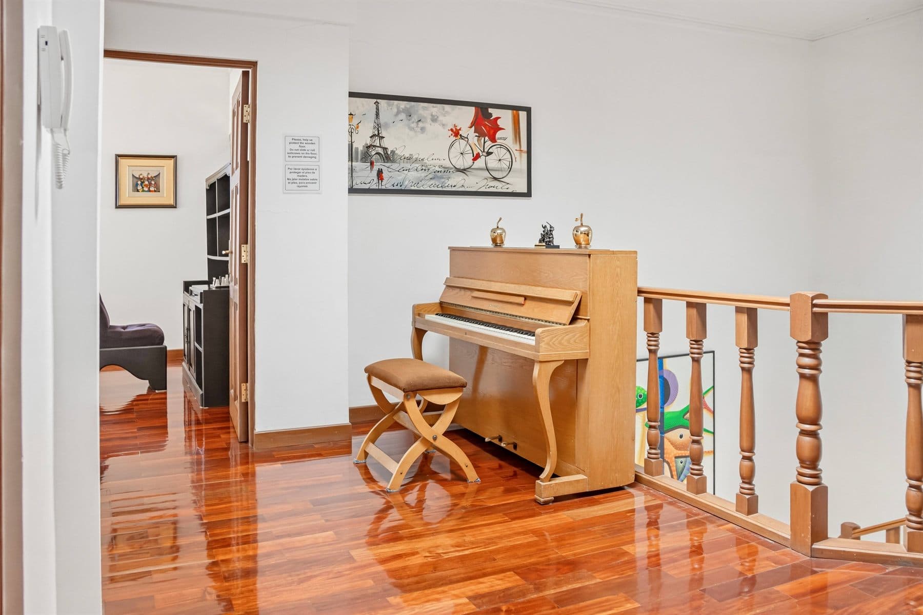 Lounge with upright piano, wood floors and curated art, finished by the Reborn group